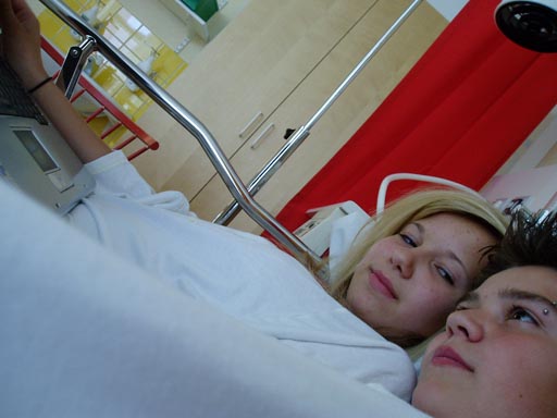Ossi and Klara are lying next to each other wearing protective clothes in a hospital bed. Klara is looking at Ossi.